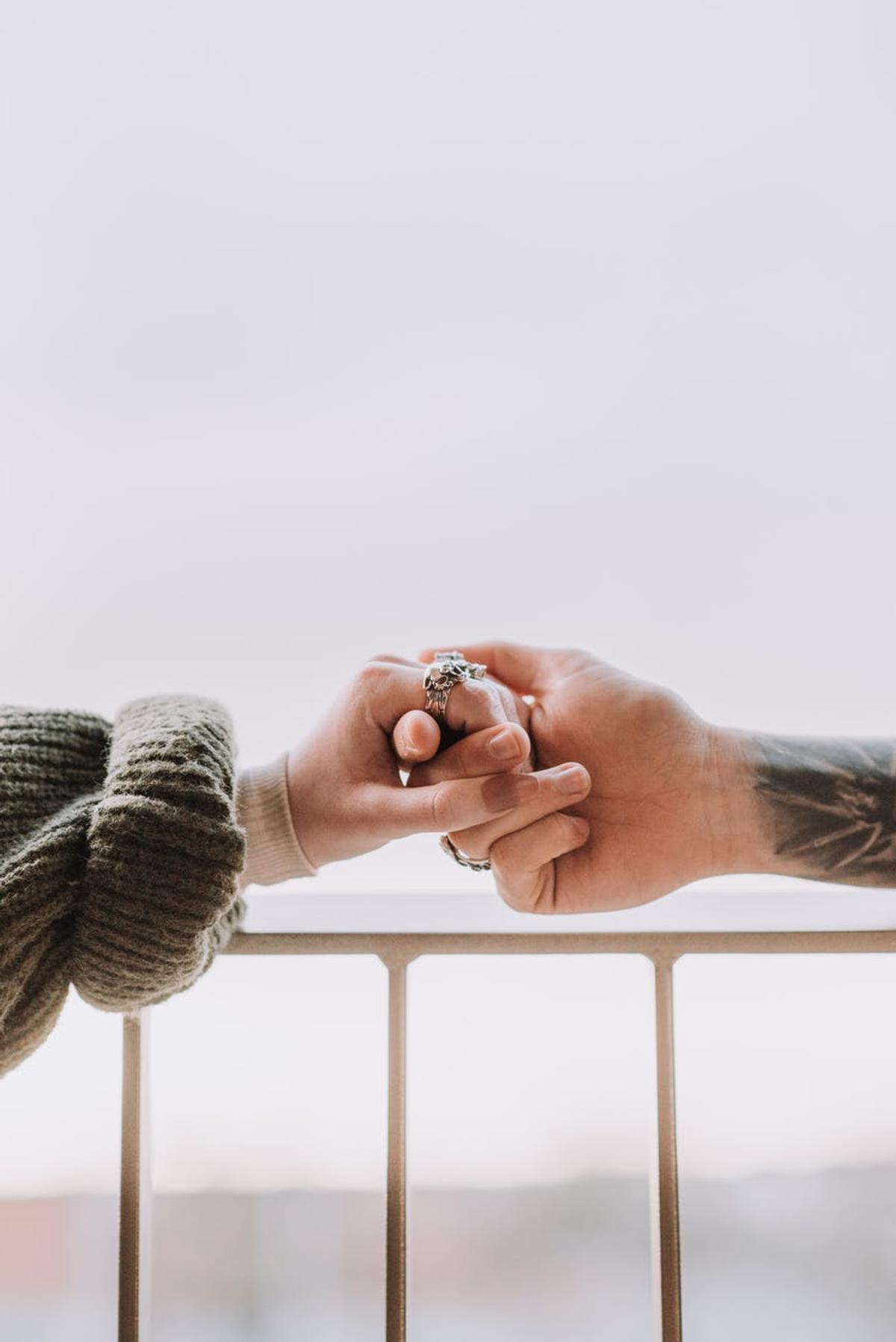 crop faceless couple holding hands on balcony
