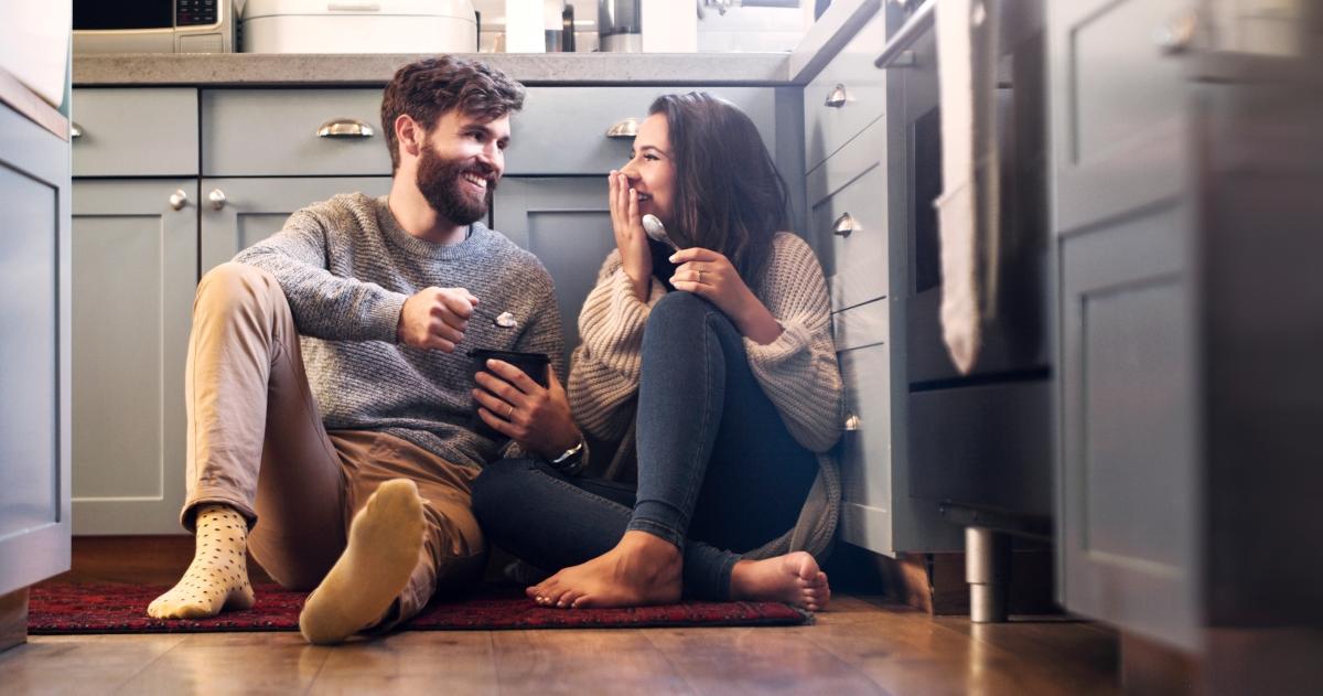 Shot of a happy young couple sharing a tub of ice cream in their kitchen at home