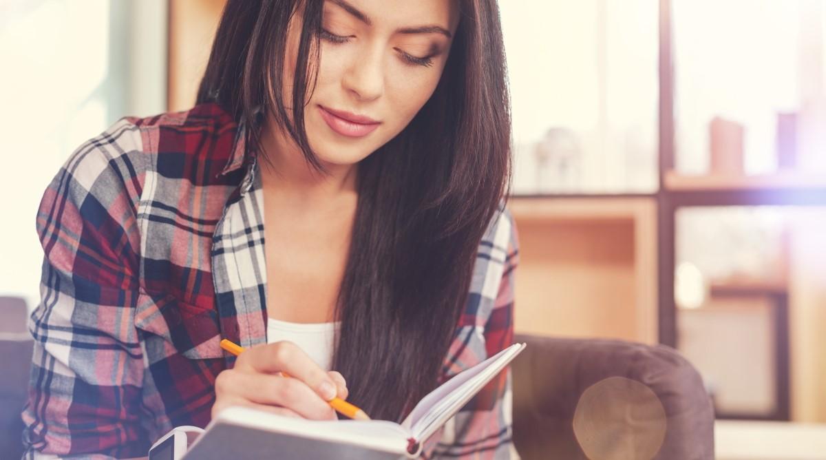 Woman with dark hair writing down a note