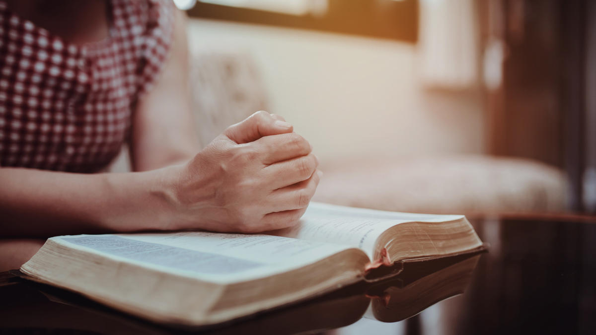 kobieta czyta Biblię siedząc na kanapie
