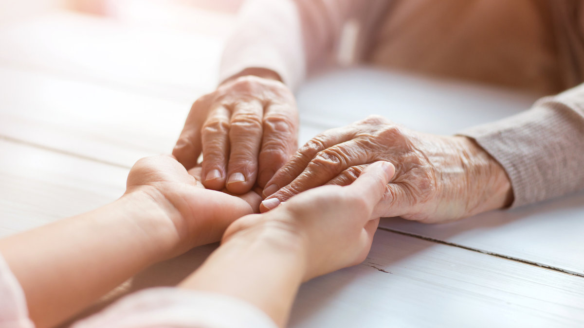 Unrecognizable grandmother and her granddaughter holding hands.