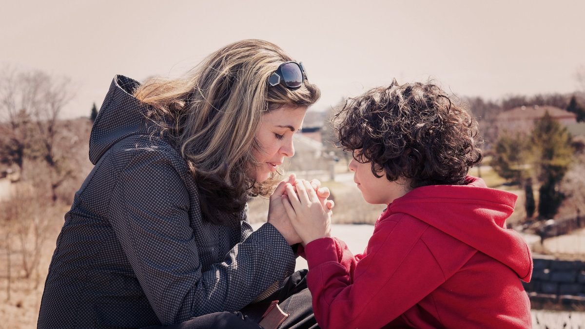 Single mother and her son having a devotional outdoors. Praying for the city with instagramesque effect