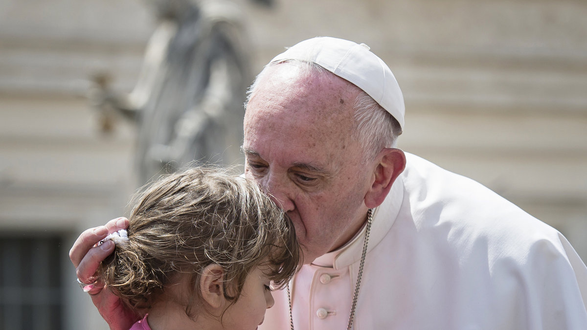 Pope Francis kisses and blessing a little girl