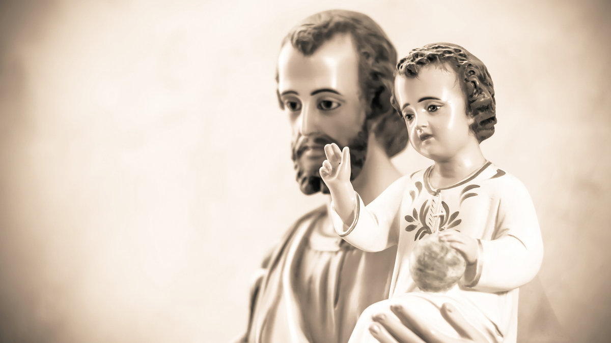 Artistic vintage sepia edit of a classical church statue of baby Jesus blessing, held by St Joseph. Artistic selective focus.