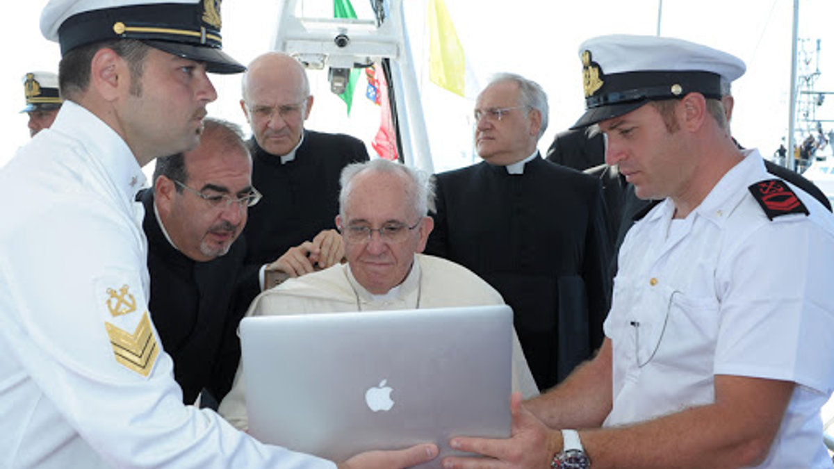 Pope Francis looking at a computer while receiving explanations on a boat off Lampedusa island – AFP – fr