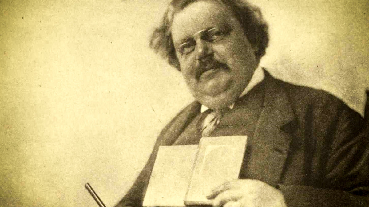 web-gk-chesterton-holding-book-pen-hector-murchison-public-domain-via-wikipedia