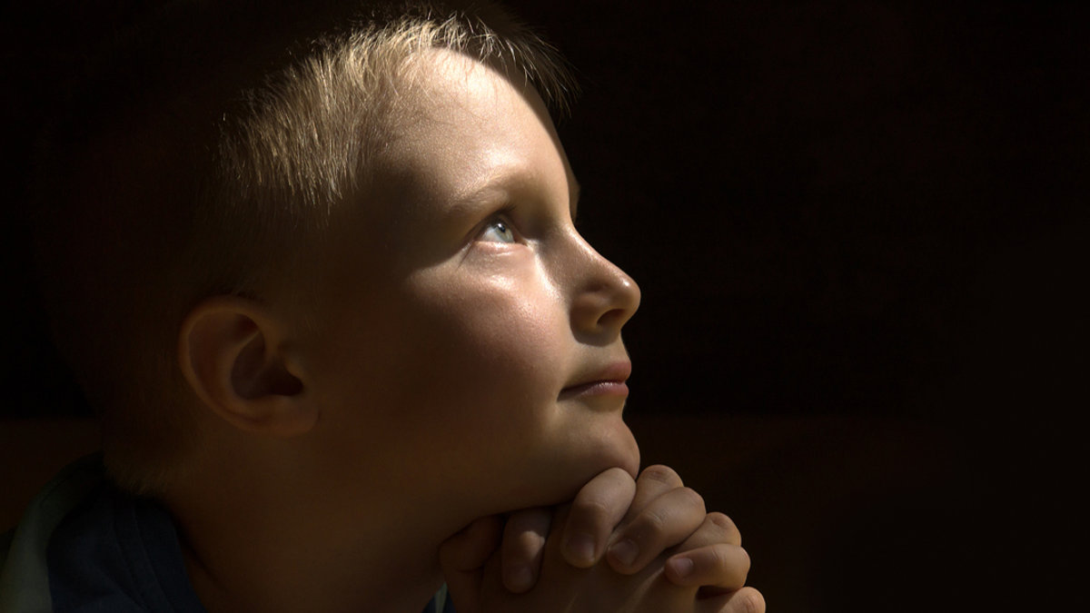 web-young-child-praying-dark-background-oksana-mizina-shutterstock_3034049721.jpg