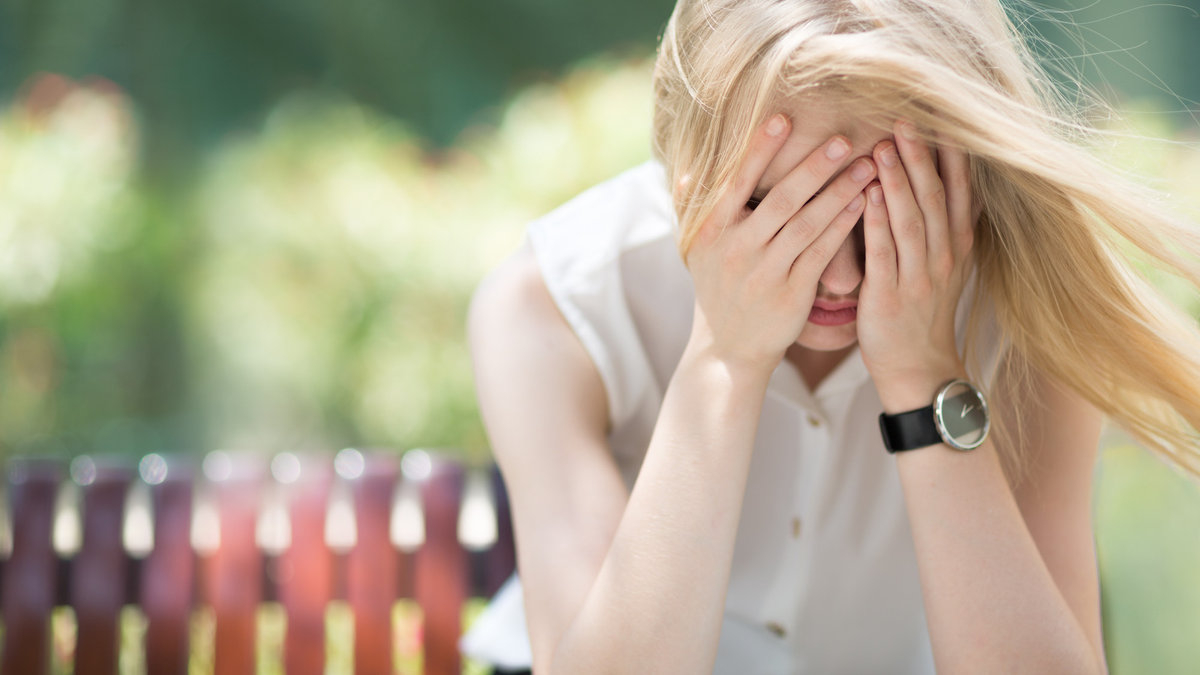 Sad woman sitting on bench outdoors