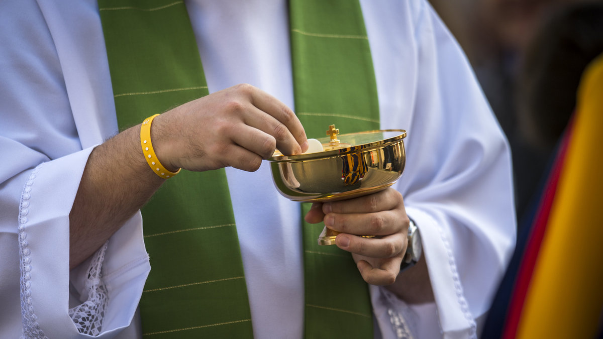Catholic priest giving beliver a Holy Communion