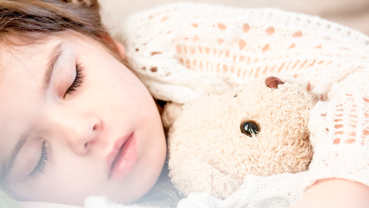ENFANT QUI DORT AVEC PELUCHE
