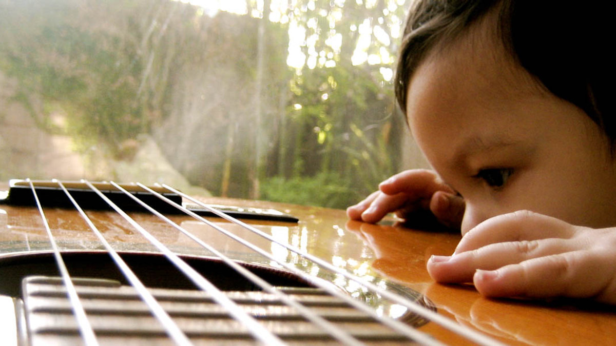 CHILD LOOKING AT GUITAR