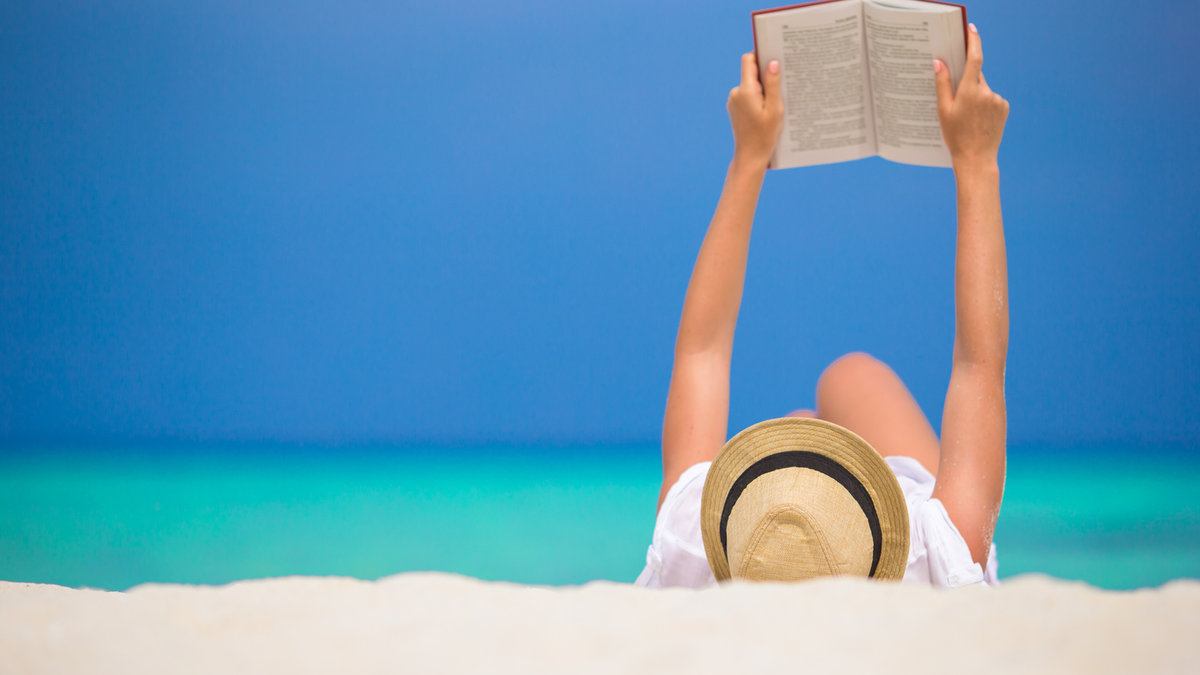Young woman is reading on tropical white beach