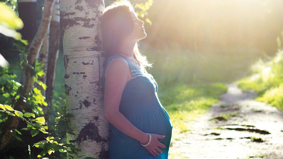 Pregnant woman standing in forrest an drelaxing