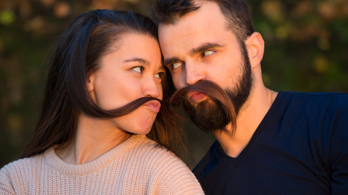 web3-young-beautiful-couple-in-the-park.-they-fool-around-and-have-fun.-they-make-false-mustaches-out-of-hair.-they-are-illuminated-by-a-ray-of-sunlight.-in-the-background-autumn-forest..jpg