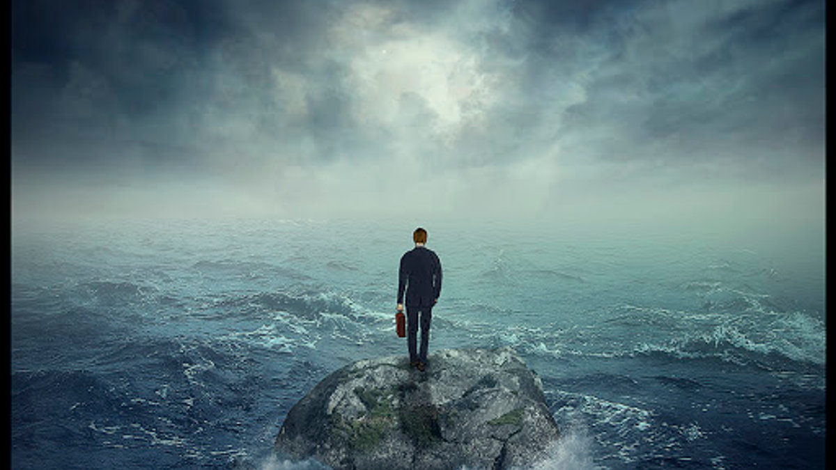 Lonely young man on a rock cliff island surrounded by an ocean storm waves © PathDoc / Shutterstock