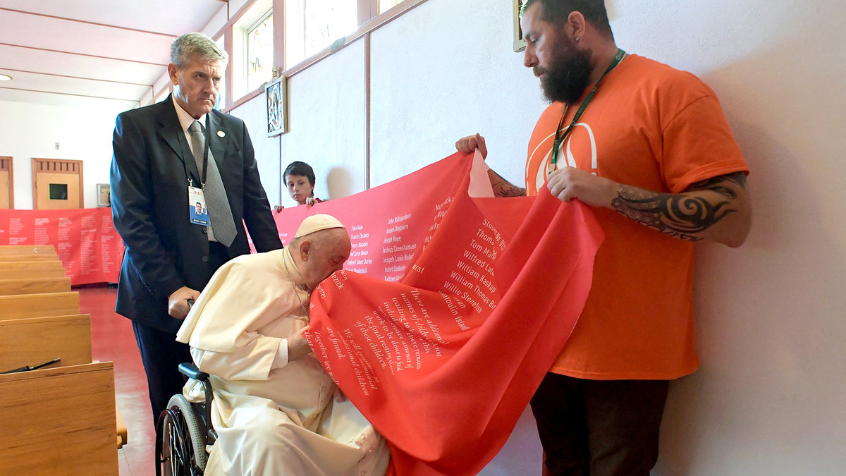 Pope Francis kissing a banner with names of victims of abuse committed at residential schools run by the Catholic Church,