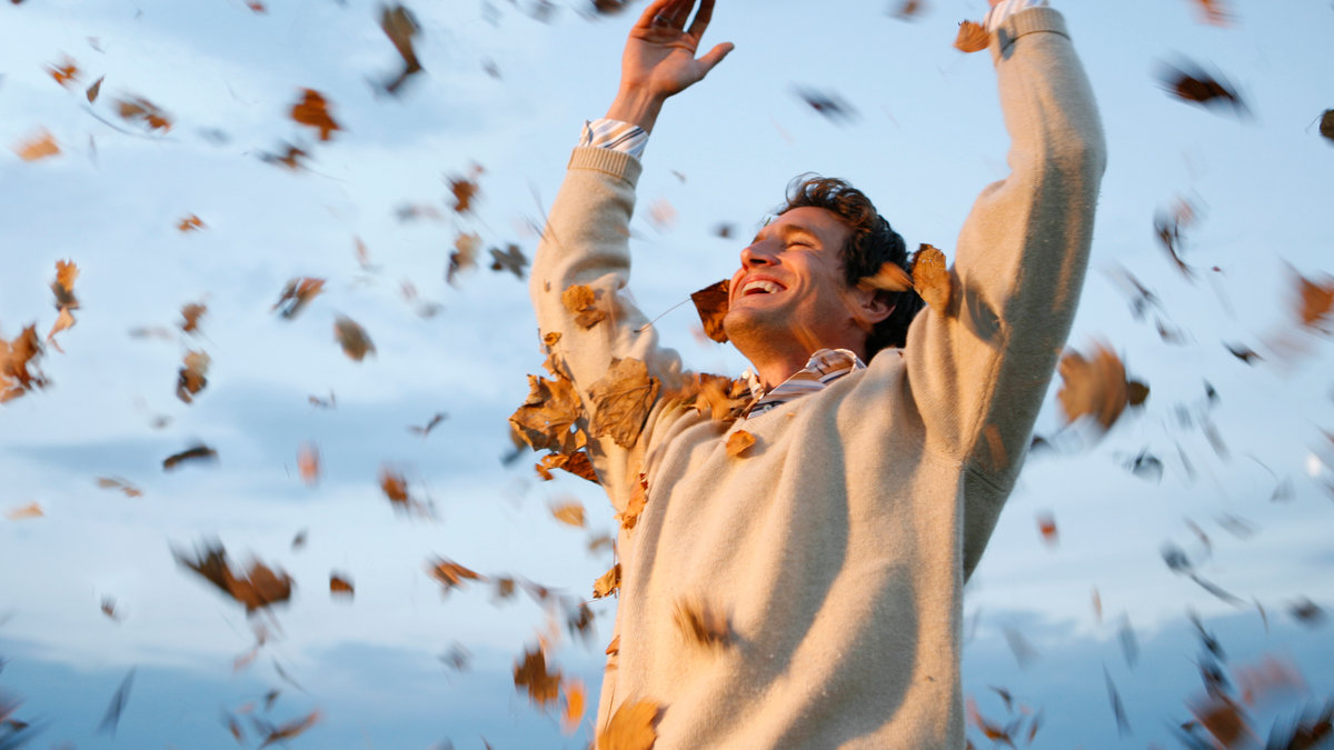 Man throwing autumn leaves in air