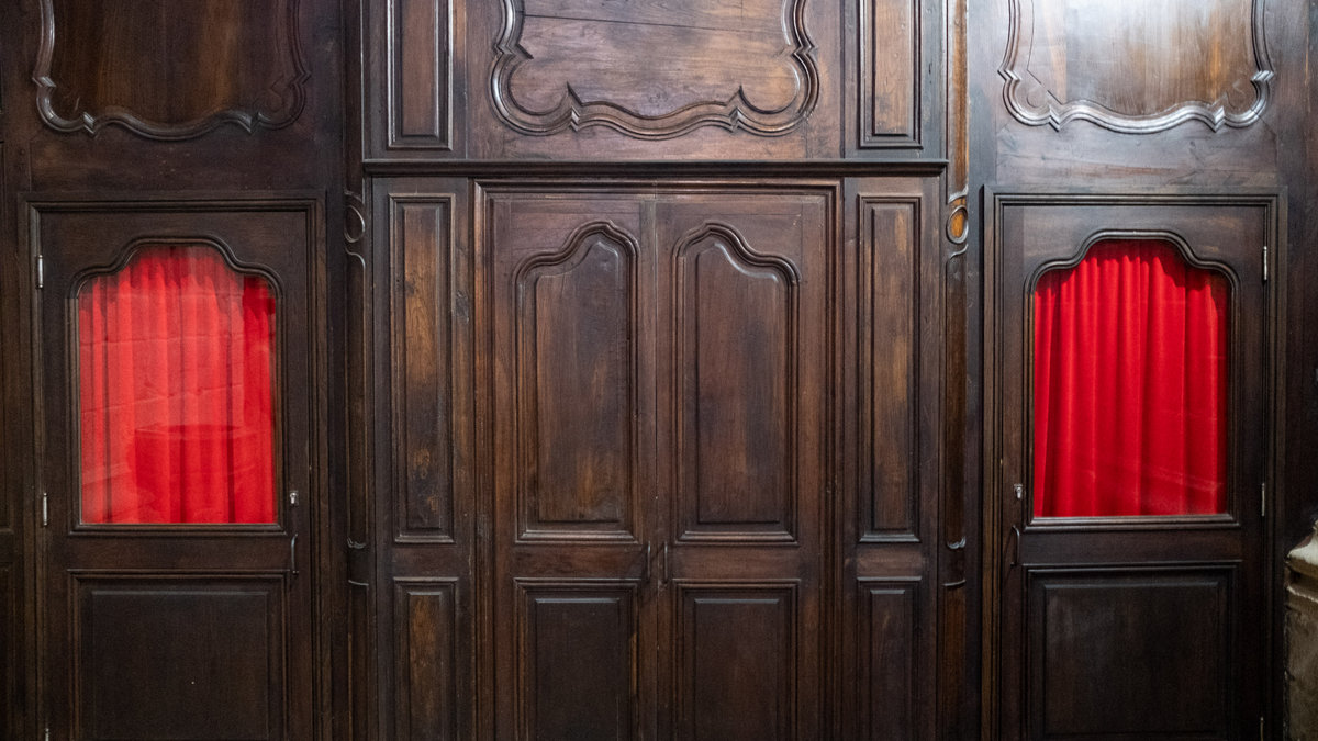Exterior view of old confessional with red curtains