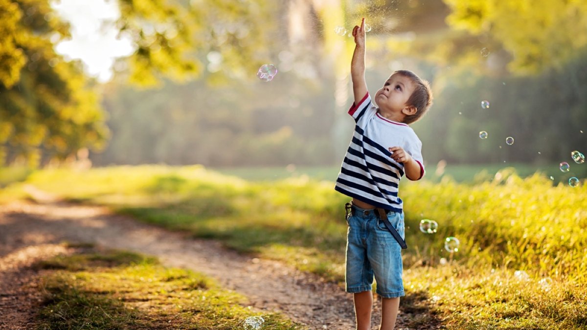 Boy in a park, chasing bubbles