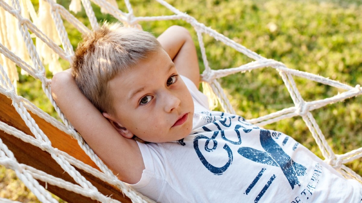 little boy is resting and dreaming in a hammock