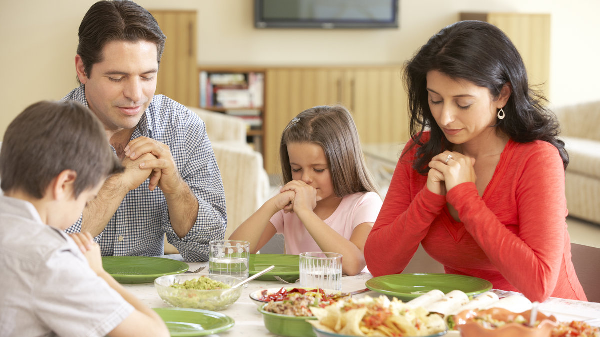 Joven-familia-hispana-dice-oraciones-antes-de-comer-shutterstock_280356143.jpg