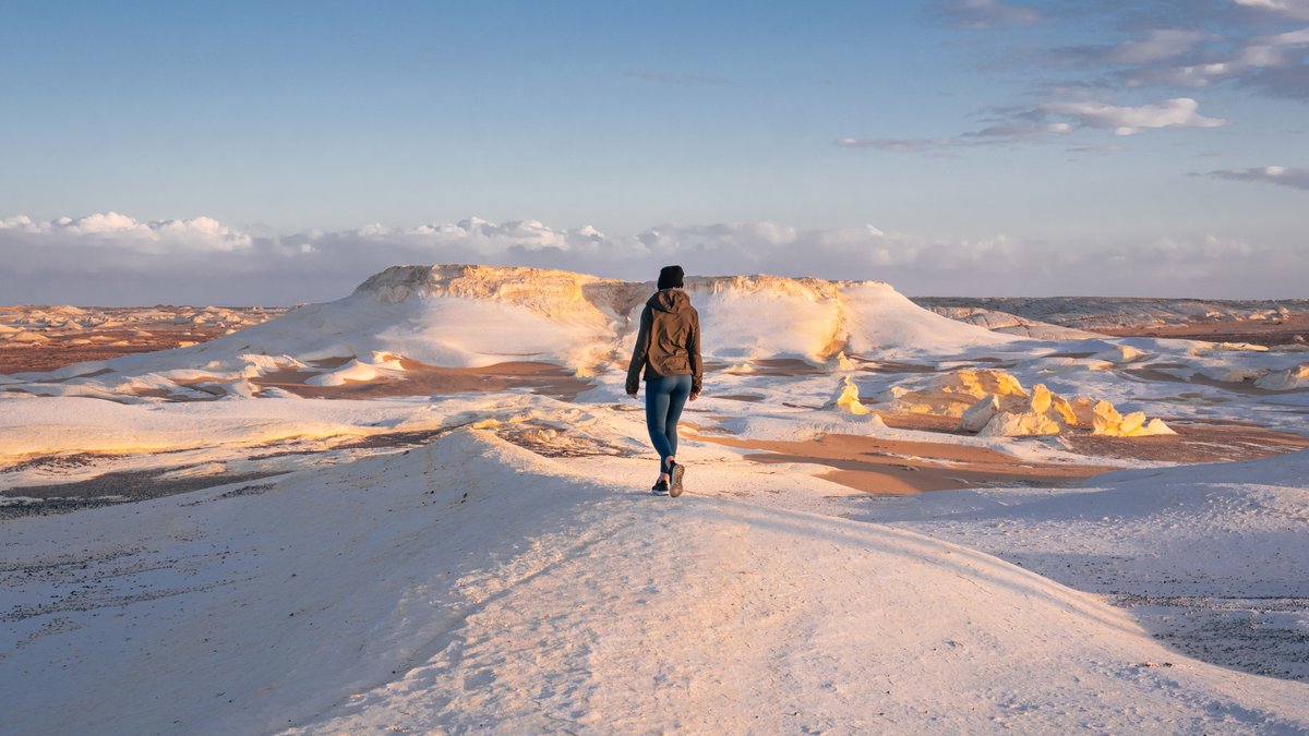 Mujer-caminando-por-el-paisaje-en-la-Montana-de-la-Nieve-Desierto-Blanco-Egipto-shutterstock_2258990721.jpg