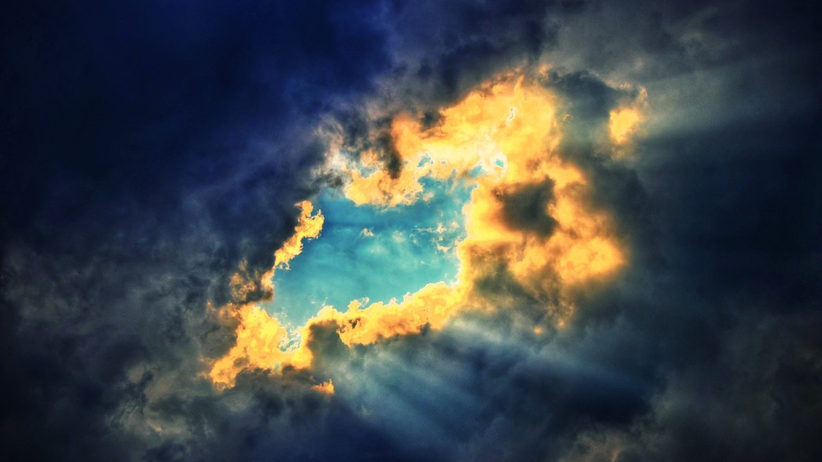 sunbeams streaming through breaking dark clouds