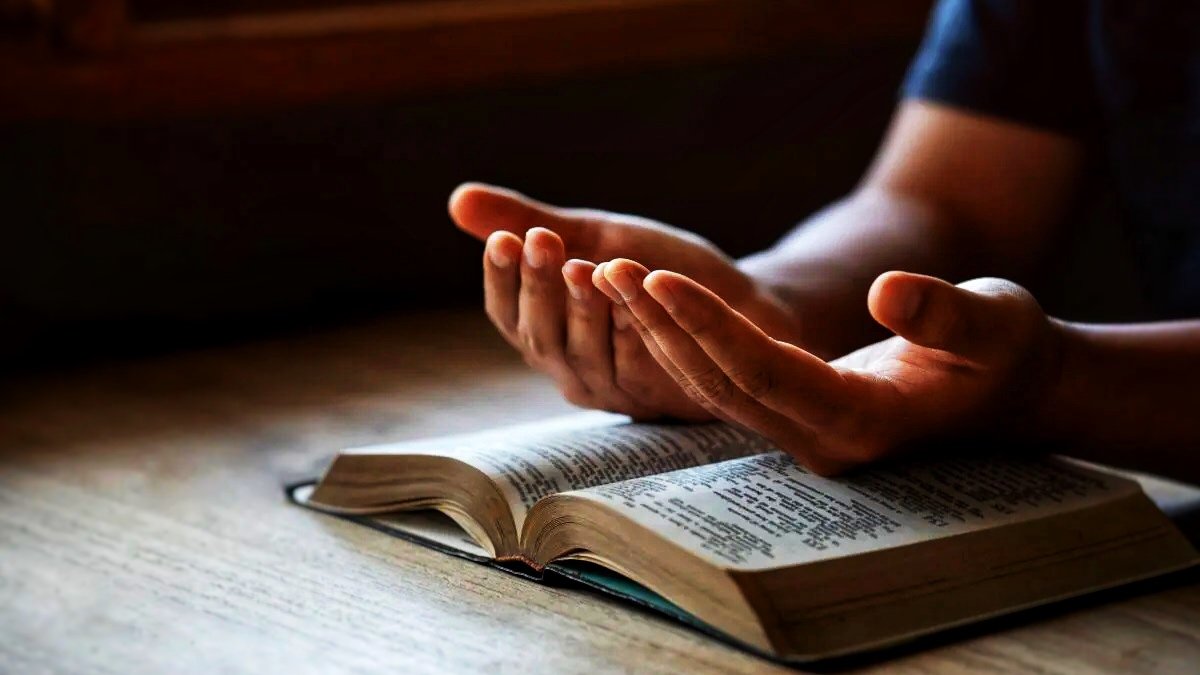 Pair of hands praying over a Bible
