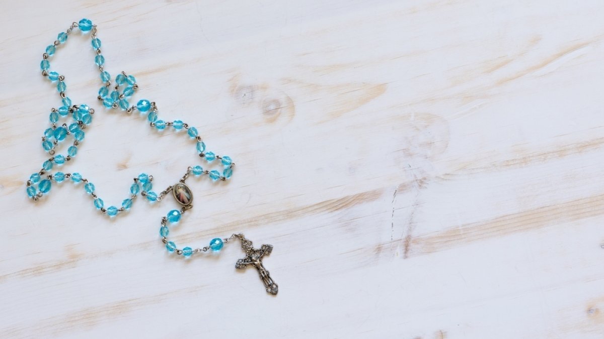 Crystal blue rosary on white wood background with copy space