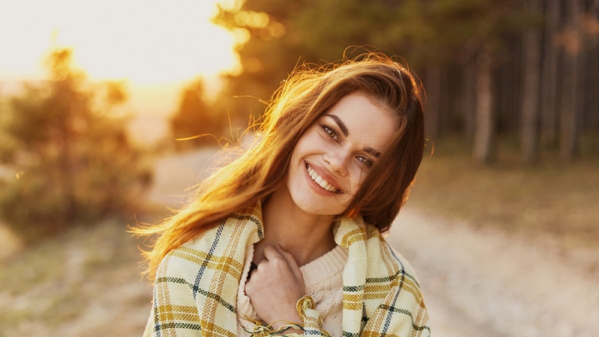 Happy woman with bread on her shoulders laughs front view and sunset in the background