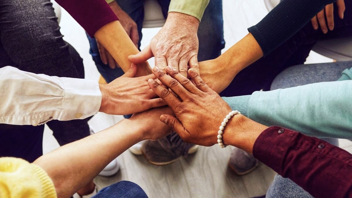 People of different ages and nationalities fold their hands on each other, symbolizing their unity and support. Team of people who are set up for productive work and a positive result. Close up.