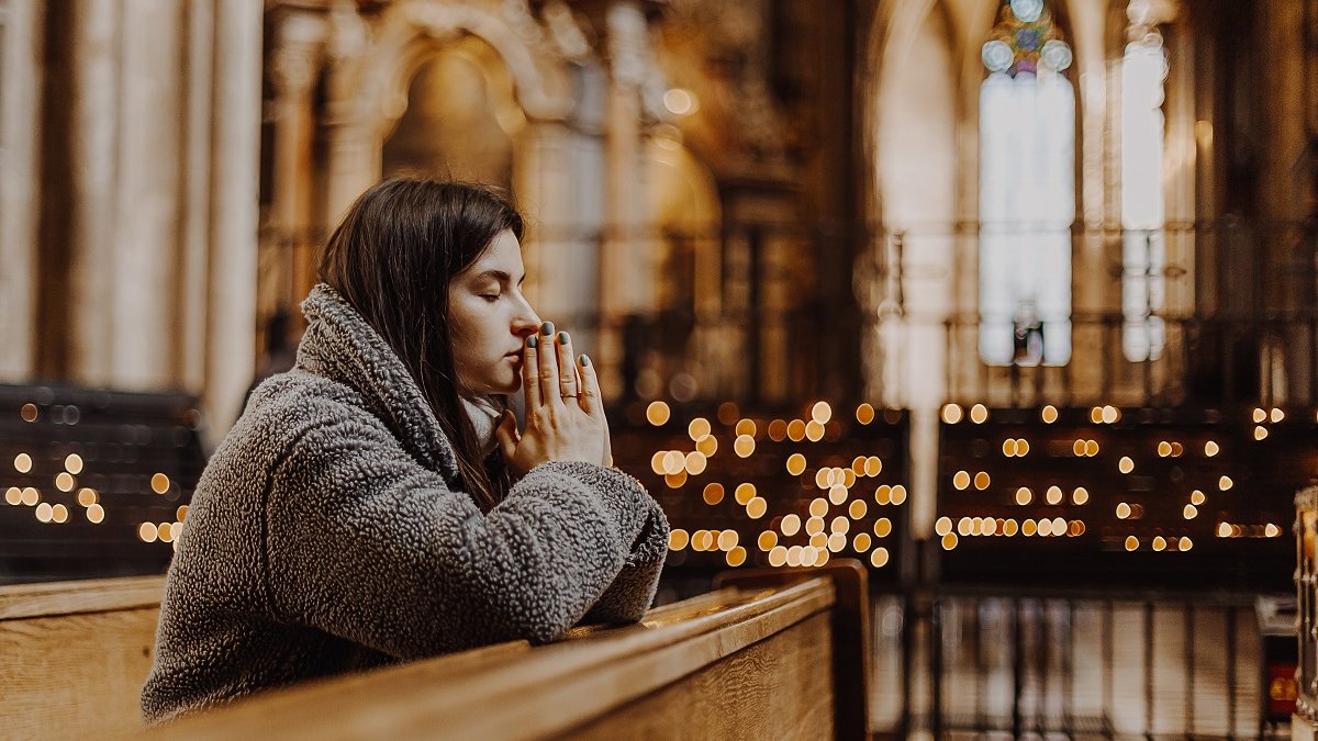 Woman praying in church with candles