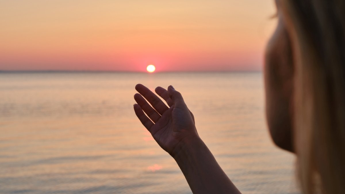 Girl looks at the sunrise by the sea