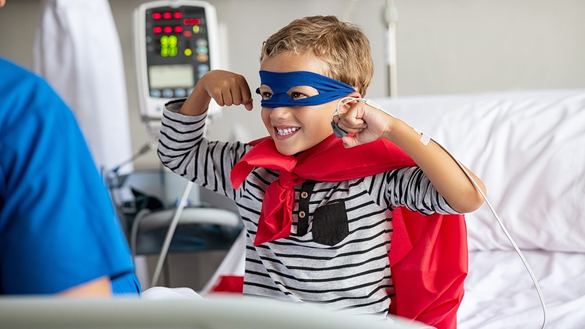 Child dressed as superhero in hospital bed