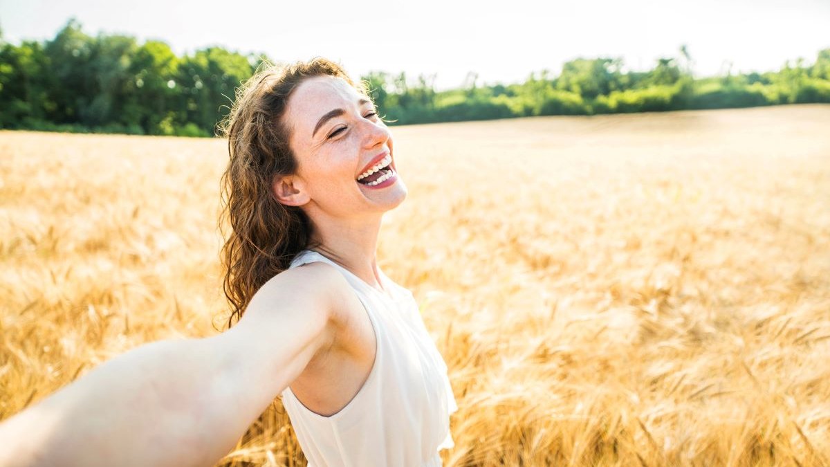Happy-woman-with-arms-outstretched-enjoying-freedom-in-a-wheat-field-shutterstock_2328881253