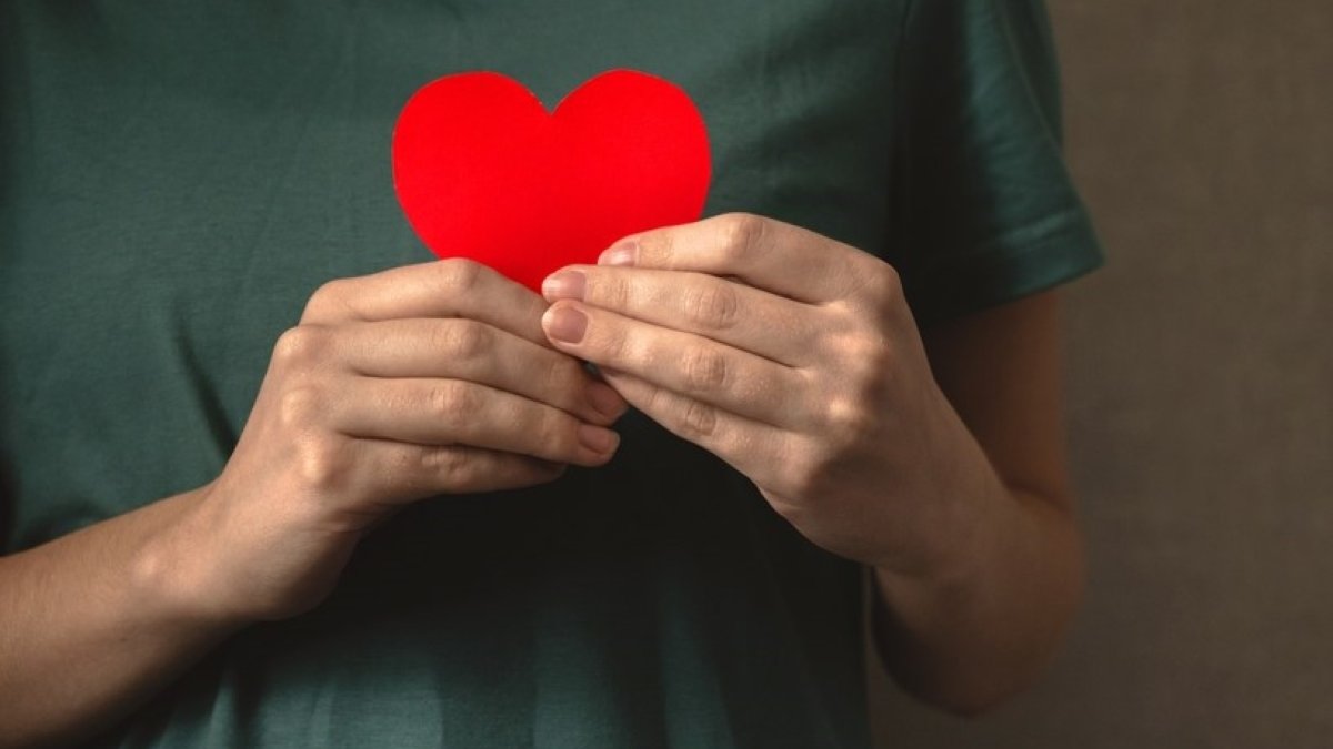 Lady holding red heart close to the body
