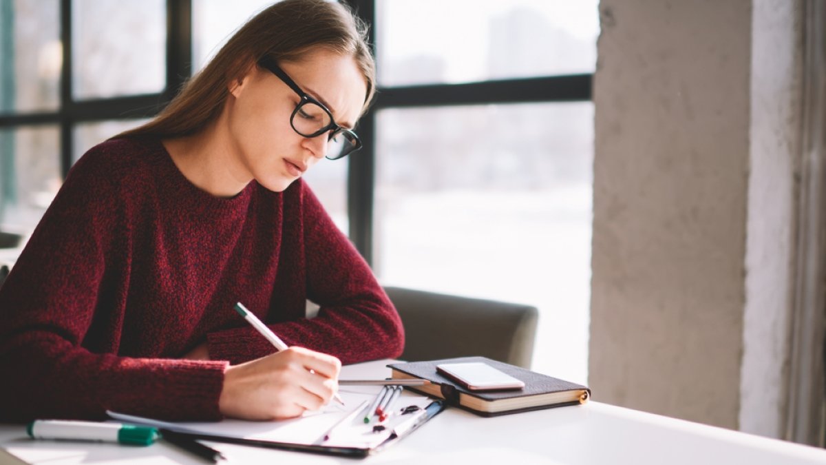 Young concentrated female student sitting in university cafe