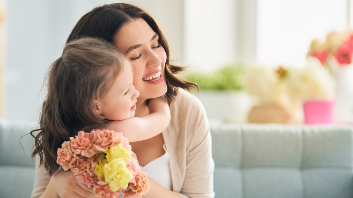 Child daughter congratulates mom and gives her flowers.