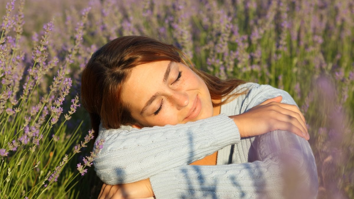 Happy woman relaxing with closed eyes sitting in lavender field