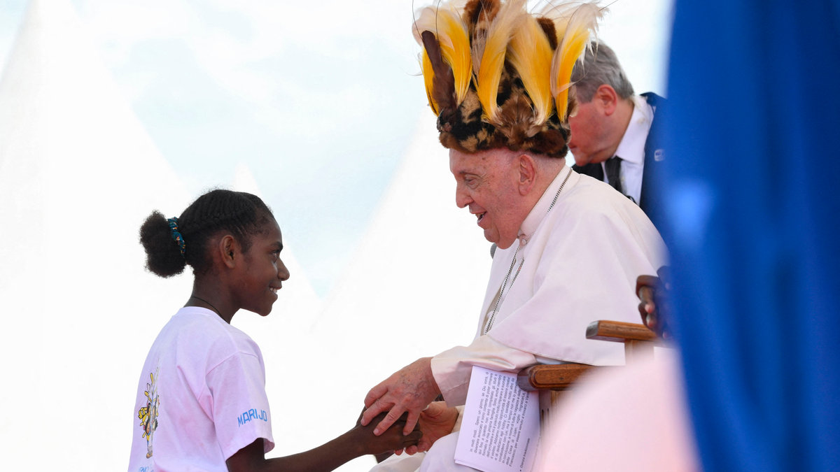 Pope Francis, seen wearing a traditional headdress, interacting with a youth during a meeting with Catholic faithful of the diocese of Vanimo in front of Holy Cross Cathedral in Vanimo, Papua New Guinea, on September 8, 2024