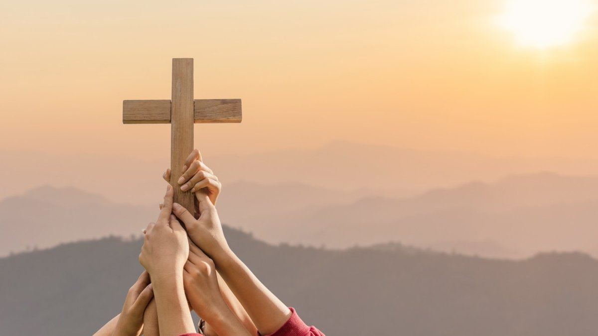 Grupa ludzi trzyma krzyż nad głową