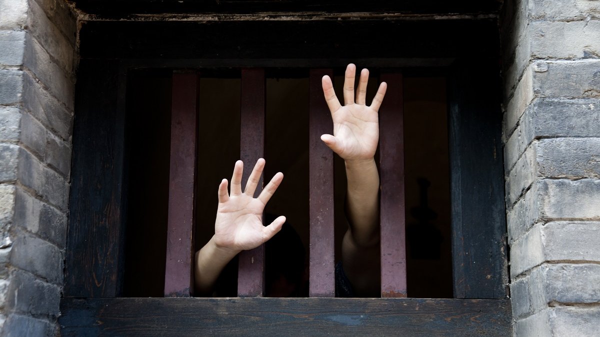 prisoner hands reach out from bars