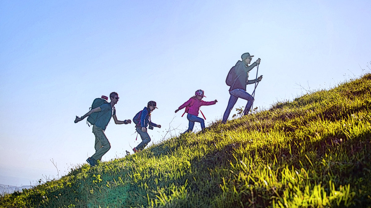 Family hiking up a hill in line