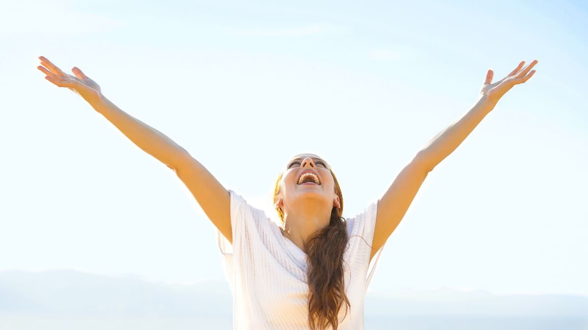 Femme-souriante-bras-leve-dans-le-ciel-bleu.jpg