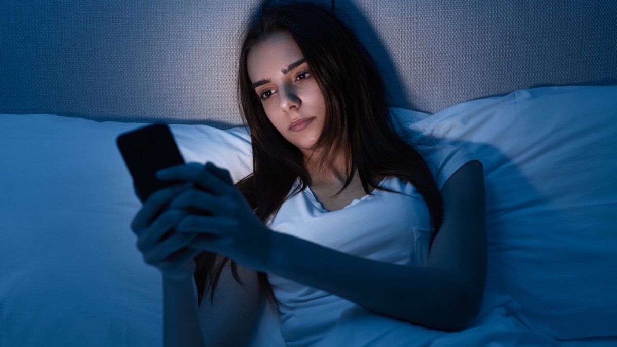 Young female having insomnia browsing social media