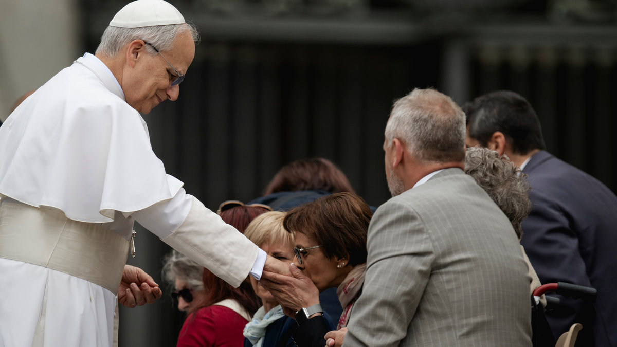 A woman kisses the hand Pope Leo XIV at the end of his first weekly general audience at St Peter's Square in The Vatican on May 21, 2025