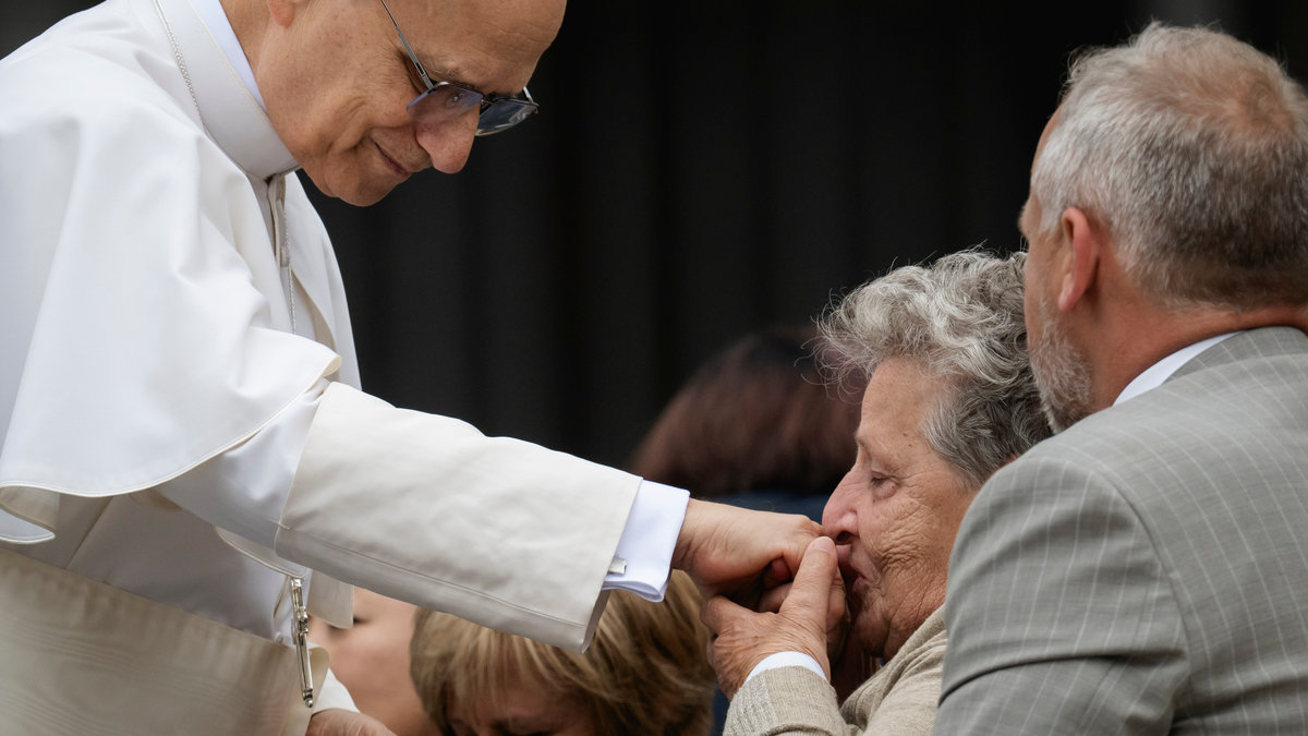 A woman kisses the hand Pope Leo XIV at the end of his first weekly general audience at St Peter's Square in The Vatican on May 21, 2025