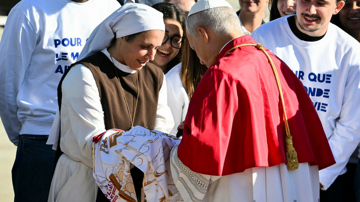 Pope Leo XIV (R) signs an autograph to a nun upon his arrival at the Orly airport, in the outskirts of Paris, on September 25, 2026