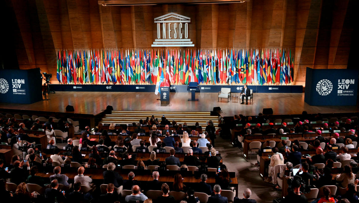 Pope Leo XIV delivers a speech on stage, next to UNESCO Director-General Khaled El-Enany (R), during a visit at the UNESCO