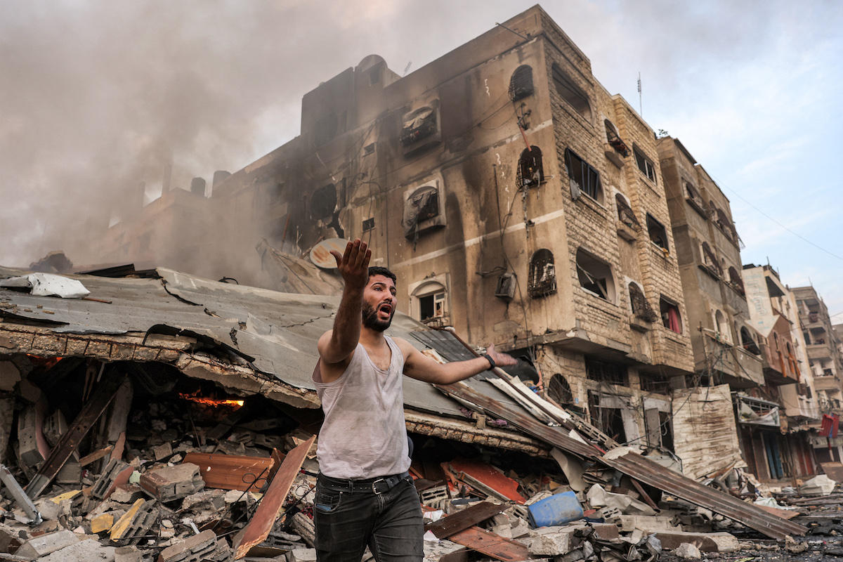 Man shouts in front of bombed Gaza building